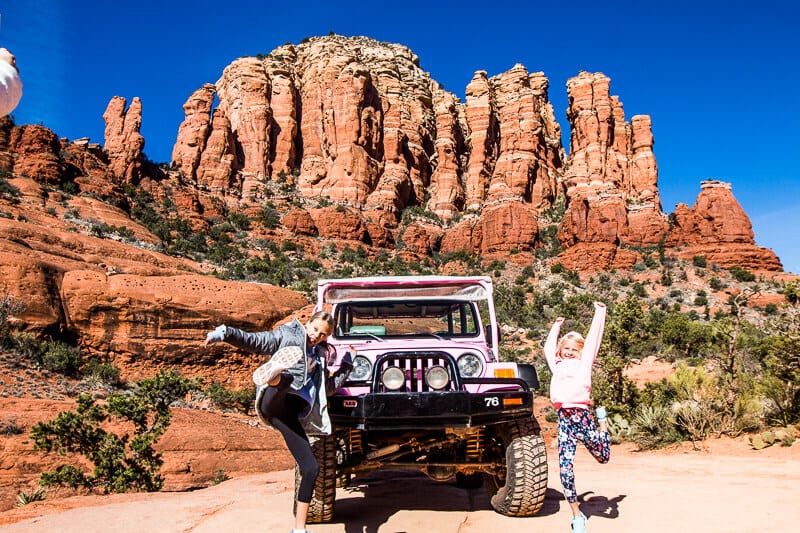 pink-jeep-tour-sedona-az (15) two girls jumping in front of pink jeep in sedona