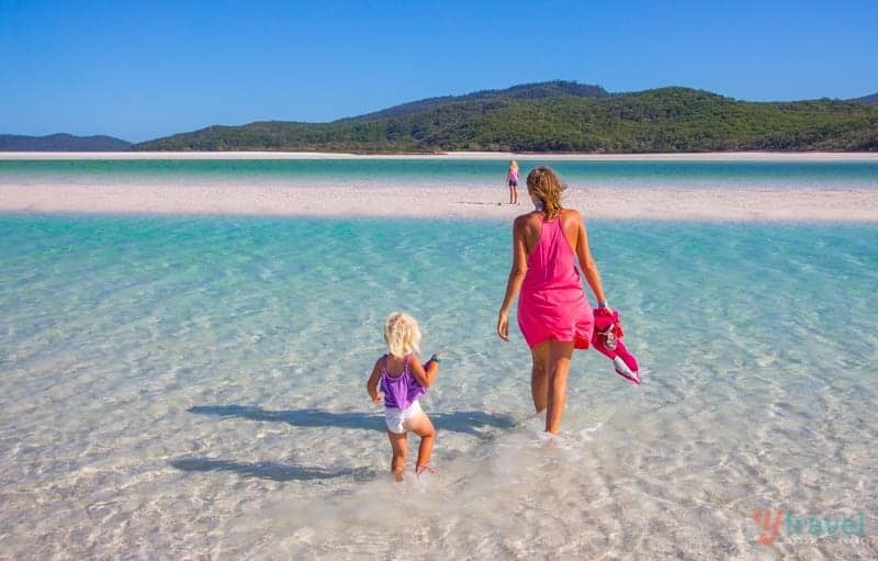 woman and child walking in the shallow waters of Whitehaven Beach